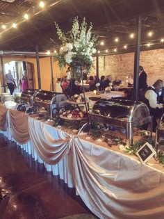 the buffet table is covered with white cloths and decorated with greenery on it