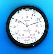 a black and white clock on a blue wall with the letters abc and person below it