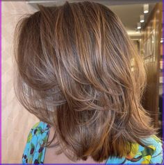 the back of a woman's head with long brown hair and highlights on it