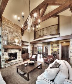 a living room filled with furniture and a fire place under a chandelier hanging from the ceiling