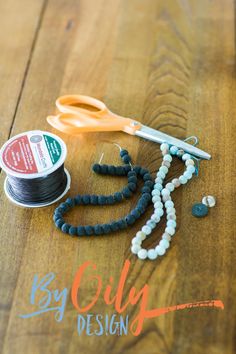 scissors, thread and beads sitting on a wooden table with the words key city design