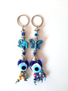 two key chains with blue beads and charms attached to them on a white table top