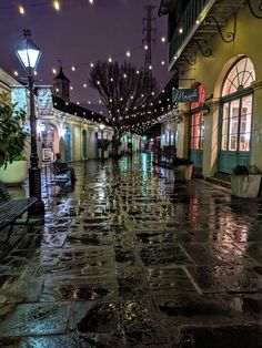 an empty city street at night with lights hanging from the ceiling and rain on the ground