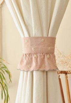 the back of a curtain with flowers and ruffles on it, in front of a potted plant