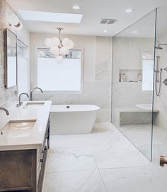 a large bathroom with marble walls and flooring is pictured in this image, there are two sinks on either side of the bathtub