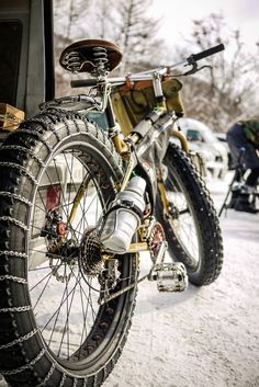 a bike is parked in the snow next to a truck with its front tire up