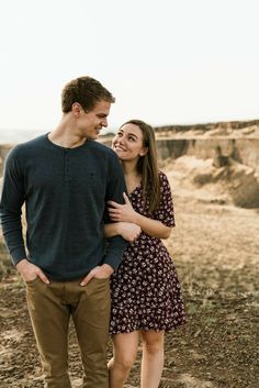 a man and woman are standing together in the desert looking into each other's eyes