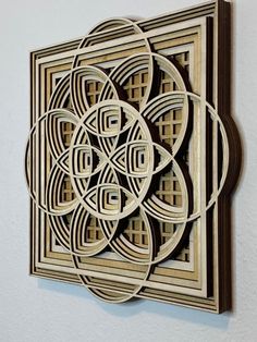 an intricately designed wooden wall hanging on the wall in front of a white wall