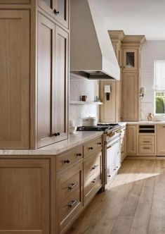 a large kitchen with wooden cabinets and white counter tops, along with hardwood flooring