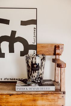 a wooden chair sitting on top of a table next to a vase and book shelf