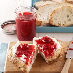 two slices of bread with jam on them next to a jar of jelly and knife