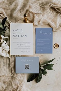 the wedding stationery is laid out on top of the bed sheet and next to some flowers