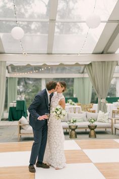 a bride and groom kissing on the dance floor in front of an open air tent