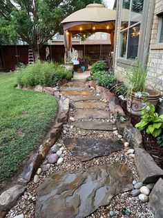 a stone path leading to a gazebo in the back yard with rocks and gravel