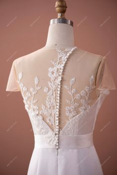 the back of a white wedding dress on a mannequinl dummy with beading