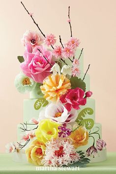 a multi - tiered cake decorated with flowers and leaves on a green tablecloth