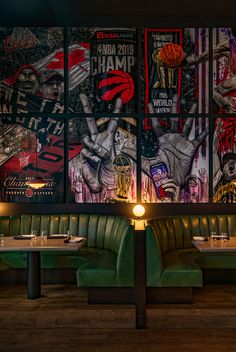 two tables with green booths in front of large posters on the wall behind them,