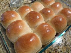 a glass dish filled with rolls on top of a counter