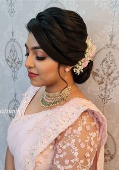 a woman wearing a white sari with flowers in her hair and jewelry on her head