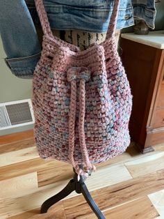 This crocheted, crossbody bag is an eclectic mix of dusty rose, teal, burgundy and ivory. The texture is rich and each stitch is well defined in the color combo. The bag measures a roomy 12" from top to bottom and 12" from side to side. The width is 4". When the bag is worn across the body, the diagonal drop across the body from the shoulder to the bag bottom is 33". This versatile bag can also be worn as a traditional tote bag by simply knotting the flexible crocheted strap. The unlined bag features a crocheted cord lock, strap and drawstring. Toss this bag into your luggage and it will be ready when you reach your destination. It is crushable and bounces back with beauty. This tote is made with double strands of Lion Brand Tape Yarn in a classic moss stitch for durability and shape reten Crochet Side Bag, Crocheted Cord, Crocheted Gifts, Teal Burgundy, Rose Handbag, Moss Stitch, Side Bags, Lion Brand, Unique Crochet