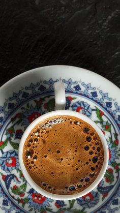 a cup of coffee on top of a saucer with an ornate design around it