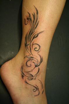 a woman's foot with an artistic tattoo design on the top of her leg