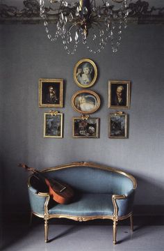 a blue couch sitting in front of a wall with pictures on it's walls