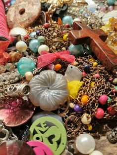 an assortment of necklaces and other items on a wooden surface with beads, chains, crosses, and pendants