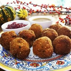 some fried food is on a plate with dipping sauces and cranberry sauce