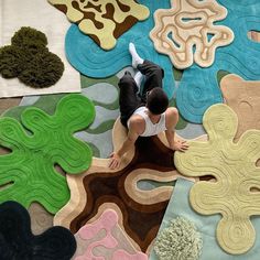 a man sitting on top of a rug covered in different colored shapes and sizes,