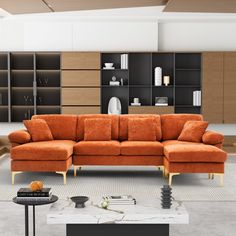 an orange couch sitting in the middle of a living room next to a book shelf