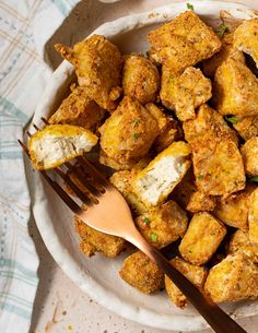 a white plate topped with fried food next to a fork