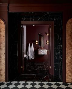 a black and white checkered floor in a bathroom next to a mirror with lights on it