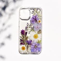 a phone case with flowers painted on the front and back cover is hanging from a tree branch