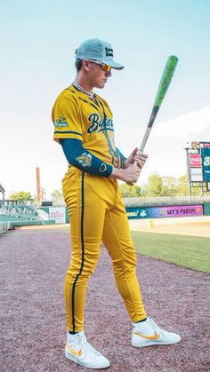 a baseball player holding a bat on top of a dirt field in front of a stadium