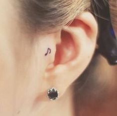 a woman's ear with a small tattoo on the left side of her ear