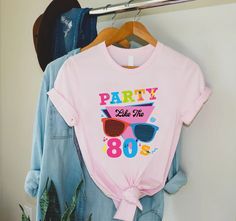 "80s Party Shirt, Party Like 80s Shirt, 80s Fan Shirt, 80s Lover Shirt, 80s Theme Party Shirt, 80s Vintage Shirt,80s Retro Shirt,80s Clothing 🎈HOW TO ORDER 1-) Please, check and review all the photos. 2-) Choose your t-shirt size and color. *Different styles of shirts may have different shades of same color choice due to different manufacturer brands. *For this reason, we recommend you to match shirts from the same styles if you want precisely matching colors (ex. Unisex, V-necks, Toddler, etc.). 3-) Click add to cart. You can go back to add more shirts. 4-)Click \"Proceed to check out\". 5-)When you check out, you can add a note to seller for any request. 🎈PRODUCT DESCRIPTION UNISEX SHIRTS * Unisex t shirt fits like a well-loved favorite, featuring a crew neck, short sleeves and designe 80 Themed Shirt, 90s Style Summer Party T-shirt, Vintage Summer Party T-shirt, Retro Pink Party Top, 90s Inspired Summer Birthday T-shirt, 90s Summer Birthday Tops, 90s Style Summer Birthday Tops, 90s Summer Tops For Birthday, 80s Fashion Women