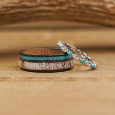 two wedding bands with turquoise stones on them sitting on a wooden table next to a piece of driftwood