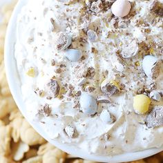 a bowl filled with white chocolate and marshmallows on top of crackers