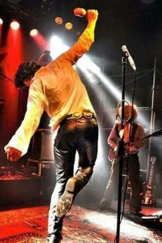 a man standing on top of a stage with his arms in the air as he sings