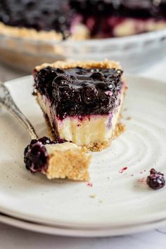 a slice of blueberry cheesecake on a white plate with a bite taken out