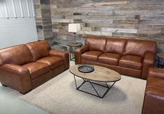 a living room with two couches and a coffee table in front of a wooden wall