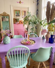 a purple table with blue chairs and plates on it in front of a pink dresser