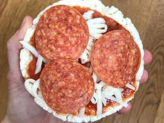 three hot dogs in a bun with cheese and sauce on top, being held by someone's hand