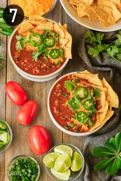 three bowls filled with chili and tortilla chips on top of a wooden table