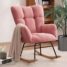 a pink rocking chair sitting on top of a white rug next to a potted plant