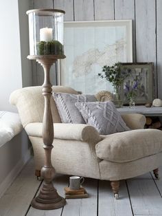 a living room filled with furniture and a lamp on top of a wooden floor next to a window