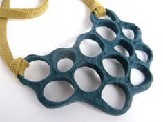 a blue and yellow necklace with holes in the middle on a white surface, hanging from a string