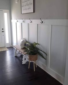 a wooden bench sitting in the middle of a room next to a wall with hooks on it