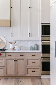 a kitchen with white cabinets and wooden floors